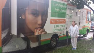 Lisa Budd, ultrasound technician, stands in front of the Thrive bus offering free ultrasounds outside of Planned Parenthood.