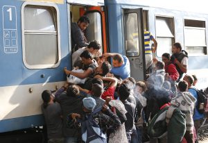 Migrants struggle to board a train at the railway station in Budapest, Hungary, Thursday, Sept. 3, 2015. Over 150,000 migrants have reached Hungary this year, most coming through the southern border with Serbia, and many apply for asylum but quickly try to leave for richer EU countries.(AP Photo/Frank Augstein)