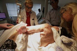 In this Sept. 26, 2015 photo, Dr. Jill Waibel, left, applies a laser to the arm of Kim Phuc to reduce the pain and appearance of her burn scars in Miami. Phuc's husband, Toan Huy Bui, stands at center with patient care coordinator, Deborah Lomax, right. While she spent years doing painful exercises to preserve her range of motion, her left arm still doesn't extend as far as her right arm. (AP Photo/Nick Ut)