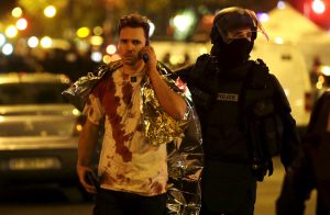 ATTENTION EDITORS - VISUAL COVERAGE OF SCENES OF INJURY A French policeman assists a blood-covered victim near the Bataclan concert hall following attacks in Paris, France, November 14, 2015. Gunmen and bombers attacked busy restaurants, bars and a concert hall at locations around Paris on Friday evening, killing dozens of people in what a shaken French President described as an unprecedented terrorist attack REUTERS/Philippe Wojazer - RTS6X0S