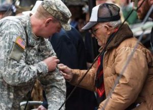 Clarence F. Dawson (Monk), veteran of the U.S. Army's 86th division company H, places a 10th Mountain patch on a 1-157th Infantry Army soldier during a re-patching ceremony Sunday at Camp Hale. Certain troops were chosen to receive their patches directly from WWII veterans like Dawson, as the first battalion, 157th Infantry became part of the third maneuver battalion of the 86th Infantry Battalion Combat Team under the 10th Mountain Division on Sunday. (photo credit - John LaConte Vail Daily)